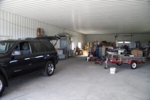 RAM 18-421 Garage space with a vehicle, storage boxes, and trailer